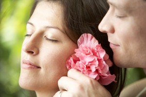 Man putting flower behind young woman's ear, side view